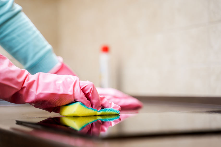 Image of female hands washing cooktop in kitchen